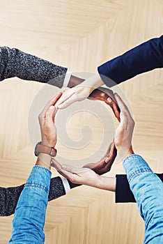 Like circle, our strength is never ending. High angle shot of a group of unidentifiable businesspeople forming a circle