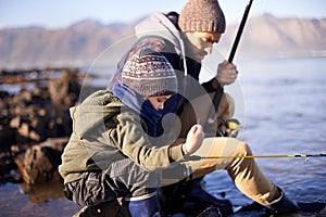 Like father, like son. a cute little boy fishing with his father by the sea.