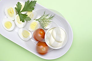 Overhead photo of vegetable salad with boiled quail egg, dill, fresh tomato and lettuce on white porcelain plate. A served salad p