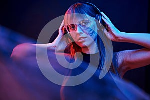 Like woman from some kind of videogame. Studio shot in dark studio with neon light. Portrait of young girl