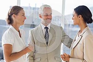 Likeable businessman speaking with female colleagues photo