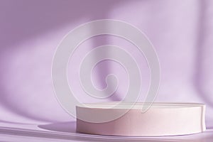 Lilac backdrop with pink round podium, display, mockup. Cosmetic product presentation with shadows and light from