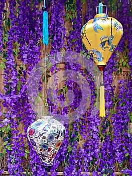 Lilac background with hanging Chinese lanterns of different colors. Chinese style fabric pendant lamps on purple background.