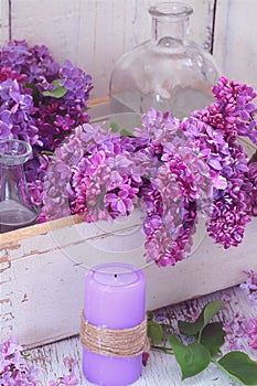 Lilac. branch of lilac in a white drawer and purple candle
