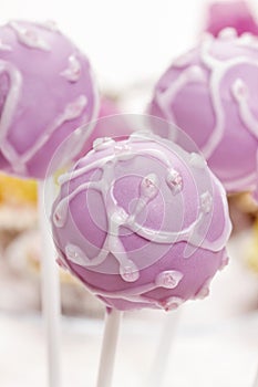 Lilac cake pops lavishly decorated with icing.