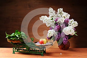 Lilac in a ceramic vase and a scale on the table