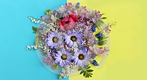 Lilac chrysanthemums, pink Tulip and lilies of the valley on a blue-yellow background. Bright flower arrangement.