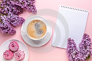 Lilac, cup of coffee, homemade marshmallow, notepad on pink background. Still life. Spring romantic mood. Top view