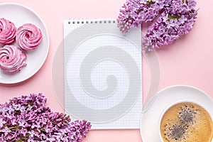 Lilac, cup of coffee, homemade marshmallow, notepad on pink background. Still life. Spring romantic mood. Top view