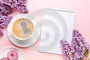 Lilac, cup of coffee, homemade marshmallow, notepad on pink background. Still life. Spring romantic mood. Top view