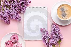 Lilac, cup of coffee, homemade marshmallow, notepad on pink background. Still life. Spring romantic mood. Top view