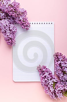 Lilac, cup of coffee, notepad on pink background. Still life. Spring romantic mood. Top view