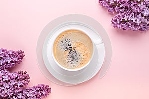 Lilac and cup of coffee on pink background. Still life. Spring romantic mood. Top view. Copy space