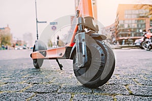 Lilac e-scooter front wheel tire perspective parked outdoor on pavement of urban city scene. Hamburg, Germany, Europe