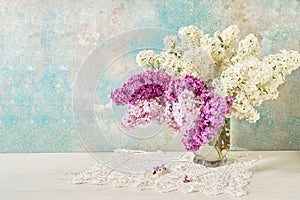 Lilac flowers bouquet in glass vase on colorful background. Copy space, Holiday background