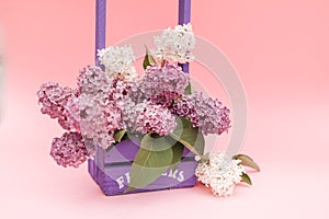 Lilac flowers bunch in a violet wooden basket over pink background. Beautiful violet Lilac flower still life Easter border design