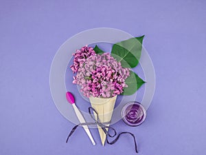 Lilac flowers in a cone with cosmetic cream.