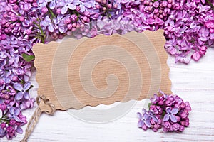 Lilac flowers and empyt card on white wooden background,