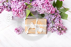 Lilac flowers, gift box on white wooden background