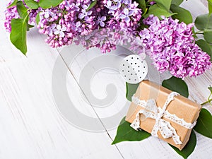 Lilac flowers, gift box on white wooden background