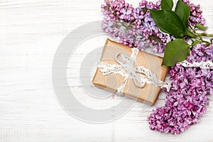 Lilac flowers, gift box on white wooden background