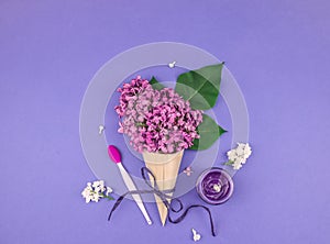 Lilac flowers in a cone with cosmetic cream.