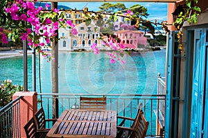 Lilac fuchsia blossom flower over hotel veranda in front of turquoise colored bay of Mediterranean sea and beautiful