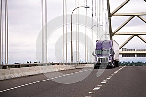 Lilac modern big rig semi truck with trailer moves along the arc