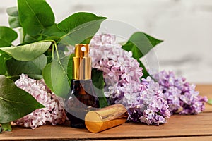 Lilac perfume - scent sprayer and blossoms on wooden table