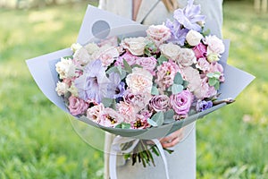 Lilac and pink pastel beautiful spring bouquet. Young girl holding a flower arrangement with various flowers. Bright