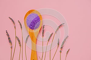 lilac salt with lavender extract in wooden spoon and lavender flowers on a pink background.purple bath salt.Flower bath