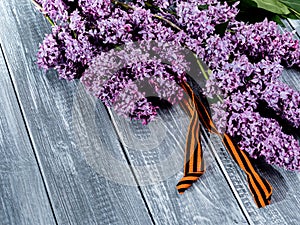 Lilac with St. George`s ribbon on a wooden background. Flowers in memory of Soviet soldiers who died during the great