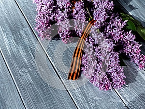 Lilac with St. George`s ribbon on a wooden background. Flowers in memory of Soviet soldiers who died during the great