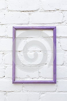 Lilac wooden photo frame on white brick wall. Copy space