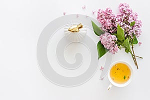 Lilas flowers bouquet with tea on working office table desk. Top view