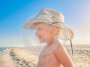 Lilltle Baby looking at the ocean, playing on the seaside in summertimes. Baby having fun with the sand. Summer rest