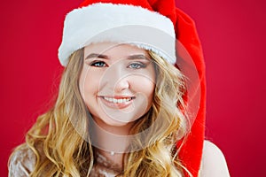 a lilt beautiful woman in a Santa Claus hat on a red background.