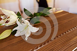 Lily flower on wooden coffin at funeral in church