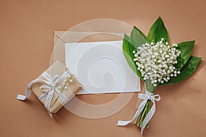 Lily of the valley and empty notepad with text copy space on beige background