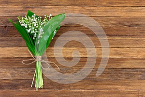 Lily of the valley flower bouquet tied with twine on wooden retro grunge background