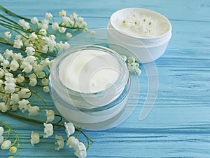 Lily of the valley flower treatment cosmetic cream on blue wooden