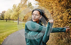 Limber muscles make all the differences. an attractive young woman stretching while out for a run in nature.