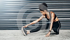 Limber up. a sporty young woman stretching her legs against a grey background.