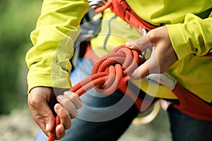 Ð¡limber wearing safety harness making a eight rope knot