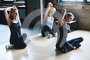 Limbering up. Full length shot of three attractive and athletic women stretching before their workout in the gym.