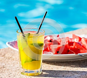 Lime cocktail in front of plate filled with red melon