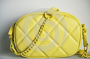 Lime cross body bag. Ladies bright-colored handbag on gray background. Yellow bag