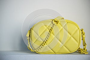 Lime cross body bag. Ladies bright-colored handbag on gray background. Yellow bag