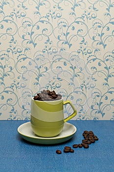 Lime green coffee cup and saucer filled with fresh coffee beans