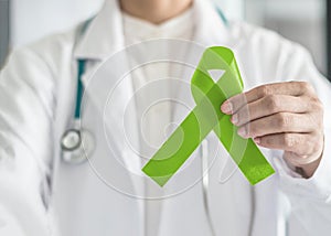 Lime green ribbon in doctorÃ¢â¬â¢s hand for Lymphoma cancer and mental health awareness, raising support and help patient living photo